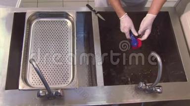 用手套煮，用清洁刷擦洗水槽中的生贻贝。 科兰德。 餐厅厨房。 流程
